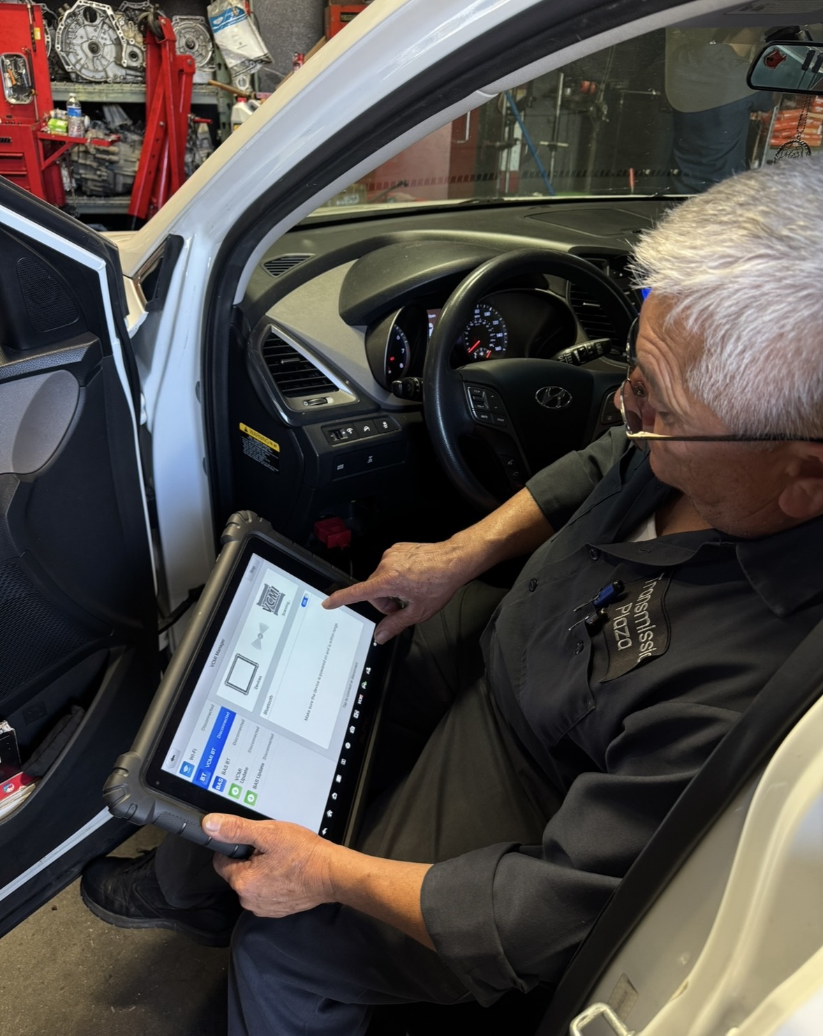 Mechanic running computerized diagnostics with a scan tool inside a vehicle