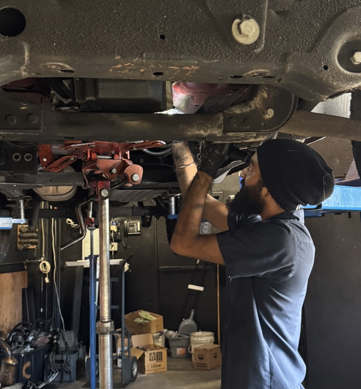 Technician removing an axle beneath a lifted vehicle